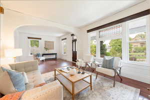 Living room with adjacent sitting room, arched doorways, and laminate wood finished floors.