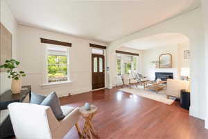 Living room with adjacent sitting room, arched doorways, and laminate wood finished floors. Natural lights flood these rooms