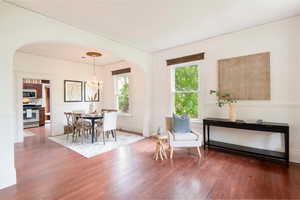 Dining area with arched walkways, wood finished floors, a chandelier