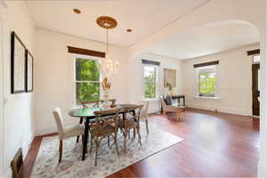 Dining area with wood finished floors, arched walkways, chandelier.