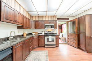 Large kitchen with stainless steel appliances, light wood-type flooring, and granite counters