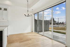 Unfurnished dining area with an inviting chandelier, light wood-style flooring, and baseboards