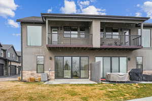 Rear view of property featuring stone siding, stucco siding, and a yard