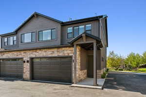 View of front of house with stone siding, an attached garage, and board and batten siding