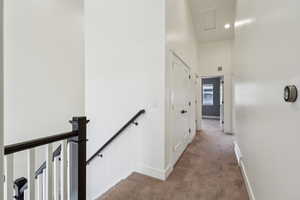 Hallway featuring baseboards, an upstairs landing, and carpet