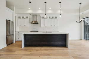 Kitchen featuring decorative backsplash, appliances with stainless steel finishes, wall chimney range hood, and a sink