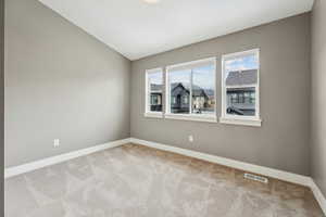 Empty room featuring lofted ceiling, visible vents, baseboards, and light carpet