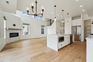 Kitchen with light wood finished floors, open floor plan, white cabinets, stainless steel appliances, and a sink