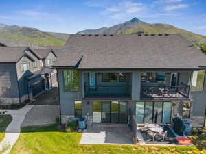 Rear view of property with a mountain view, stone siding, and a balcony