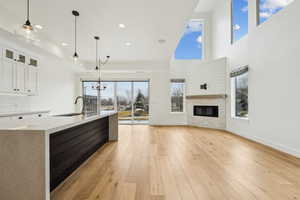 Kitchen with light wood finished floors, a sink, white cabinets, open floor plan, and backsplash