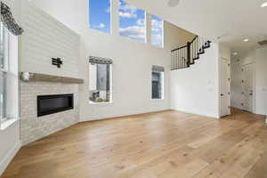 Unfurnished living room featuring a brick fireplace, light wood-style floors, and baseboards