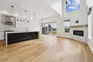 Unfurnished living room with baseboards, recessed lighting, light wood-style flooring, a glass covered fireplace, and a sink