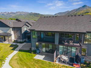View of front of home with a balcony, a mountain view, a patio area, and stone siding