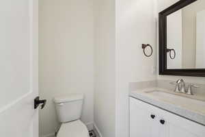 Bathroom with baseboards, toilet, and vanity