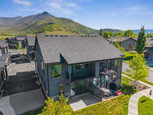 Back of house with a balcony, a patio, a residential view, stucco siding, and a mountain view