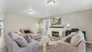 Living area with wood finished floors, baseboards, and a glass covered fireplace