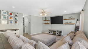 Living room featuring light wood-type flooring, a ceiling fan, recessed lighting, a fireplace, and baseboards
