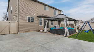 Rear view of property with a playground, fence, a gazebo, a patio, and a gate