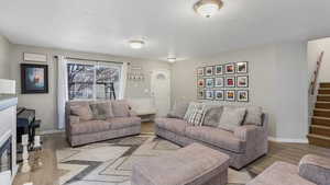 Living area featuring stairway, wood finished floors, and a textured ceiling