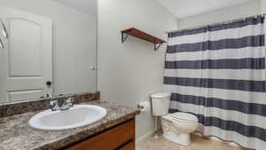 Bathroom with tile patterned floors, toilet, a shower with shower curtain, baseboards, and vanity