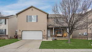 Traditional-style home featuring driveway, an attached garage, covered porch, and a front lawn