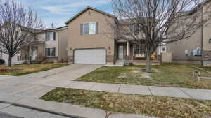 View of front of property with solar panels, an attached garage, driveway, and a front yard
