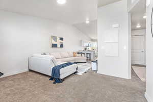Living area featuring lofted ceiling, recessed lighting, baseboards, and carpet floors