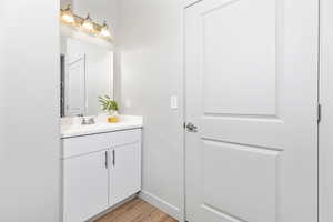 Bathroom featuring vanity, wood finished floors, and baseboards