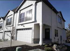 View of front facade featuring a garage, stone siding, board and batten siding, and driveway