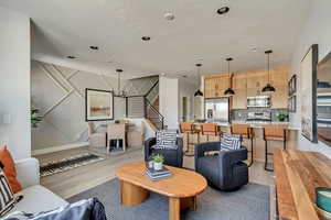 Living area with an inviting chandelier, stairway, light wood-style flooring, and baseboards