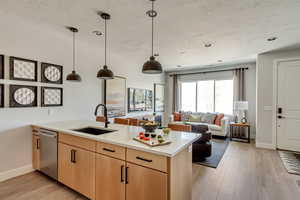 Kitchen with light brown cabinets, light wood finished floors, a peninsula, a sink, and light countertops