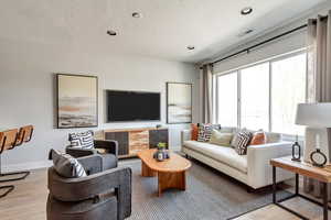 Living area featuring wood finished floors, baseboards, visible vents, recessed lighting, and a textured ceiling