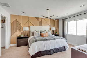 Bedroom featuring a textured ceiling, light colored carpet, visible vents, and baseboards