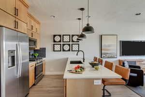 Kitchen featuring light brown cabinets, a sink, stainless steel appliances, light countertops, and light wood-style floors