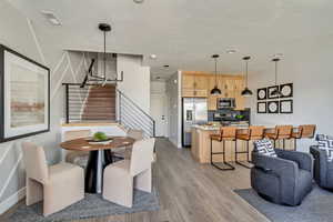 Dining room with baseboards, a textured ceiling, stairs, and light wood-style floors