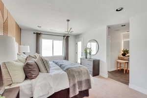 Bedroom with baseboards, light carpet, and a textured ceiling