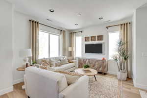 Living room with light wood-style flooring, recessed lighting, baseboards, and visible vents
