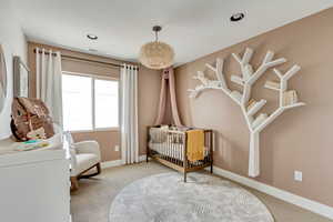 Bedroom with baseboards, visible vents, recessed lighting, a nursery area, and light colored carpet