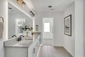 Full bath featuring double vanity, visible vents, baseboards, and a sink