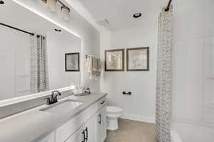 Full bathroom with vanity, a shower with shower curtain, wood finished floors, baseboards, and toilet