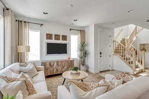 Living area with stairway, wood finished floors, visible vents, and a wealth of natural light
