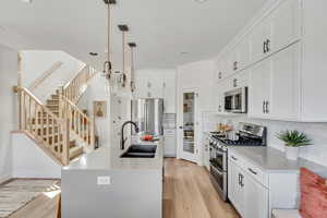 Kitchen featuring light wood-type flooring, tasteful backsplash, appliances with stainless steel finishes, and a sink