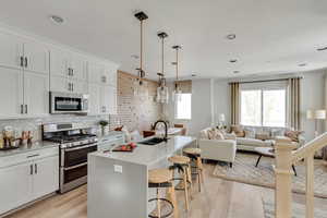 Kitchen with a breakfast bar, light wood-style flooring, a sink, open floor plan, and appliances with stainless steel finishes