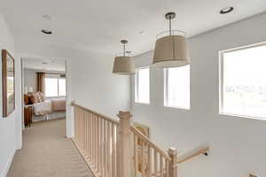 Hallway featuring an upstairs landing and light carpet