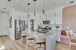 Kitchen with backsplash, appliances with stainless steel finishes, and light wood-style floors