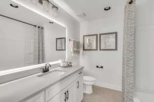 Full bath featuring toilet, curtained shower, wood finished floors, baseboards, and vanity