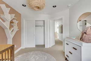 Bedroom featuring light colored carpet, a closet, and baseboards