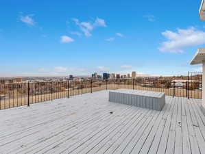 Wooden rooftop deck featuring a city view