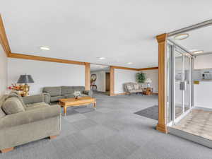 Carpeted living area with crown molding, decorative columns, recessed lighting, and baseboards