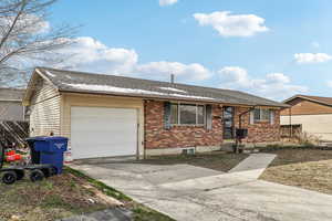 Ranch-style home featuring brick siding, concrete driveway, an attached garage, and a shingled roof